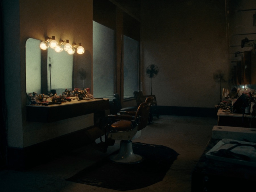 An empty barbershop chair in front of a lit mirror
