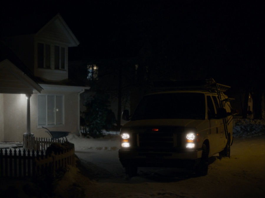 An HVAC service van in a snowy driveway at night