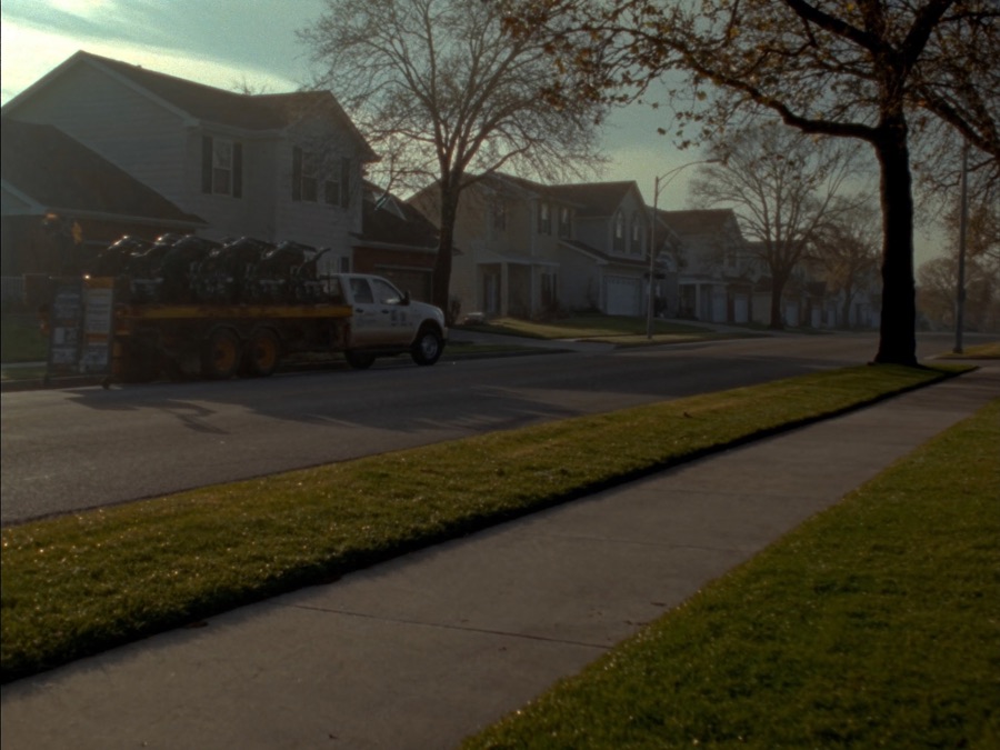 A landscaping truck and trailer on a street at dawn